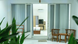 A hotel room with a bed, a TV, a desk, and two chairs. - Turtle House Lombok (Kuta)