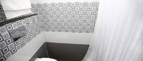 Un bagno piccolo con il water, un asciugamano appeso al muro e piastrelle decorate.