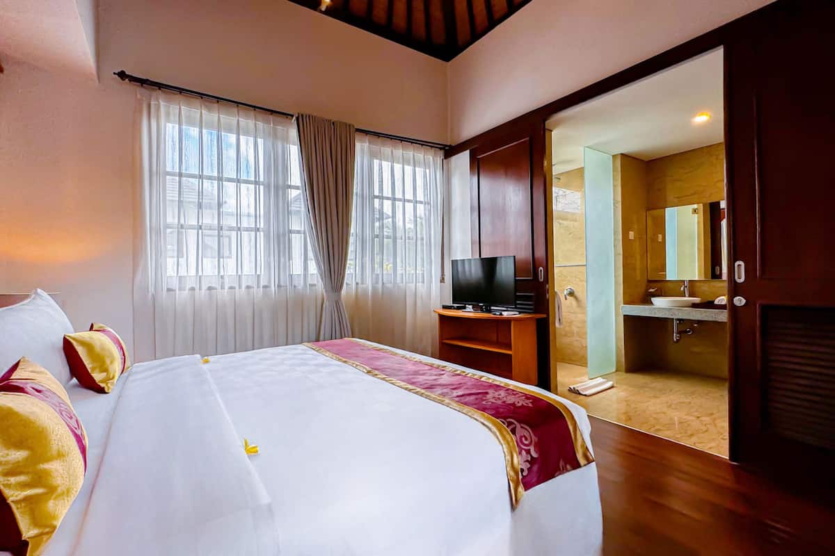 Een hotelkamer met een bed, een televisie, een badkamer met een wastafel en spiegel, en een schuifdeur naar de badkamer.