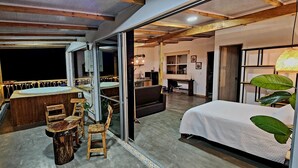A cozy room with a bed, a desk, and a small seating area with chairs. - Cabaña en la Montaña con Vista a la Ciudad Desde el Jacuzzi (Medellín)