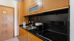 A modern kitchen with wooden cabinets, a black countertop, stainless steel sink, and a built-in stove. - GuestReady - Hideaway in Porto (Porto)