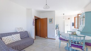 Una habitación con sofá, una mesa de comedor con sillas, un armario y una puerta que da a otra habitación.
