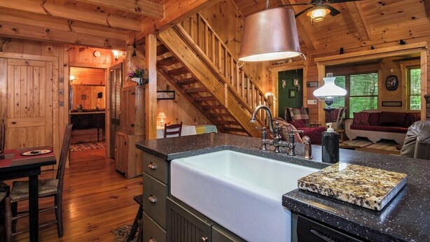 A wooden cabin interior with a kitchen, dining area, and a staircase. - Black Bear Lodge Near Dupont State Forest (Hendersonville)