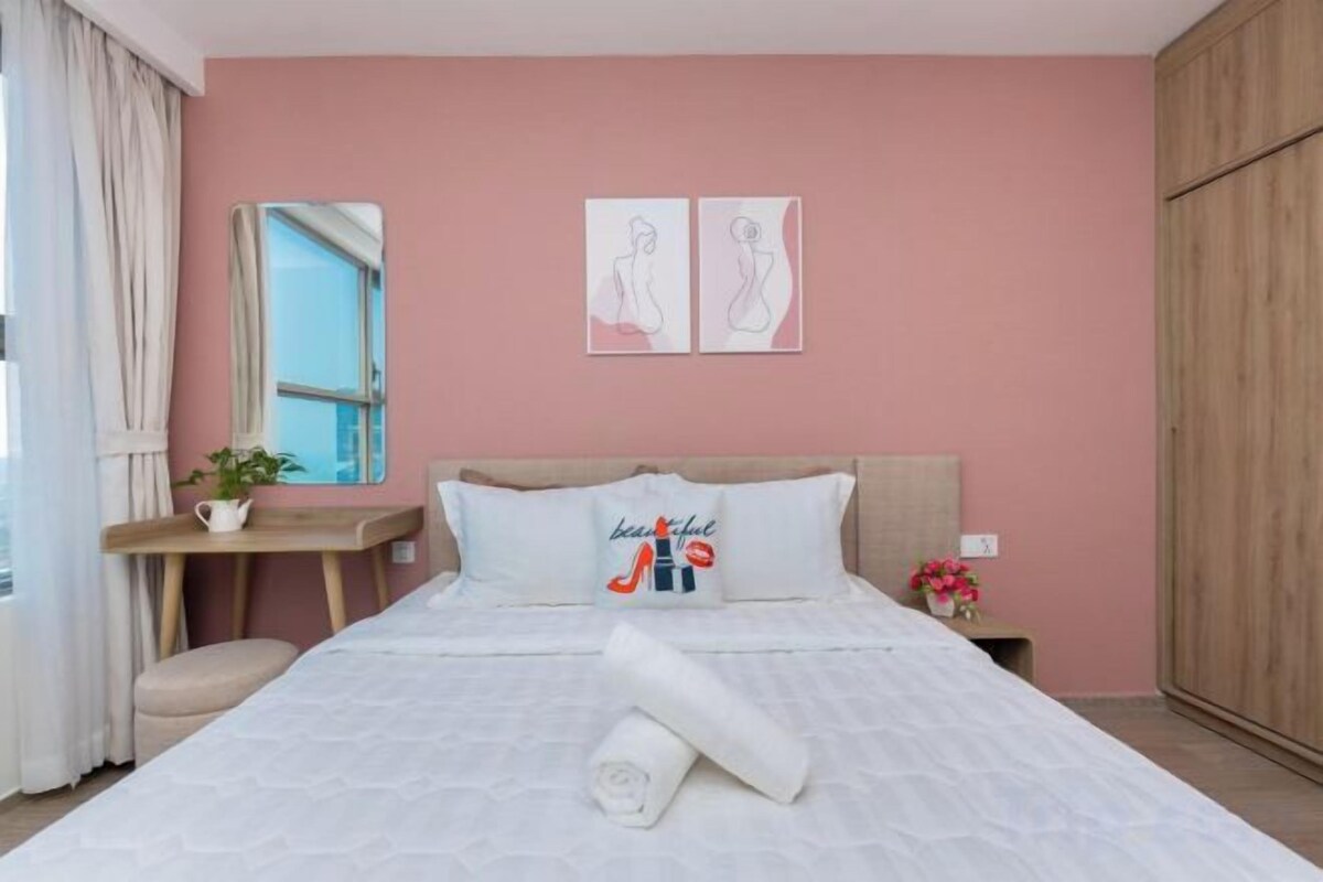 A bedroom with a bed, a bedside table, a mirror, and a window.