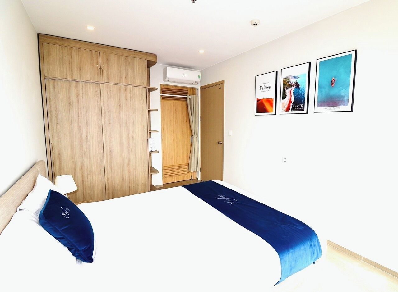 Une chambre d’hôtel comprenant un lit, une armoire, un appareil de climatisation et trois tableaux encadrés accrochés au mur.