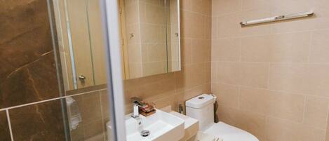 Ein Badezimmer mit Duschabtrennung aus Glas, einem weißen Waschbecken und einer Toilette.