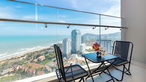 A balcony with a glass railing overlooking a beach and cityscape. - The Song Vung Tau Apartment (Ho Chi Minh City)