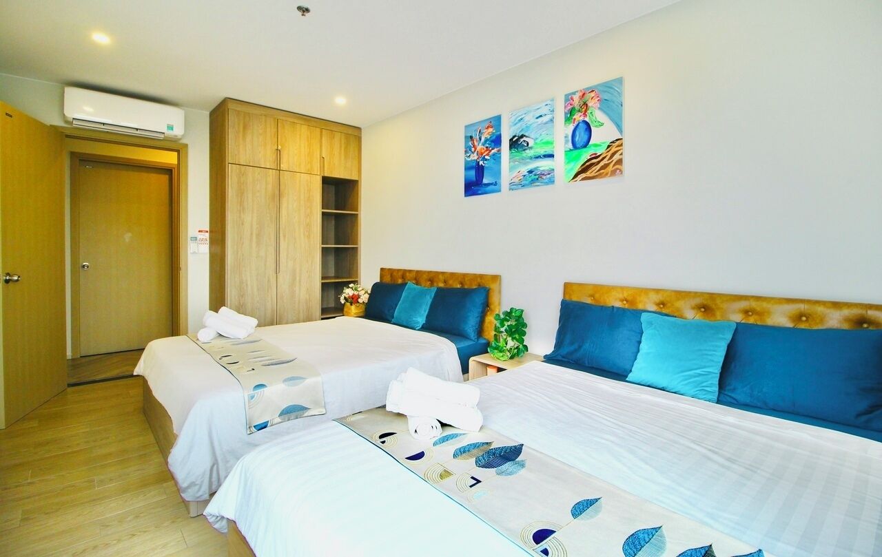 A hotel room with two beds, a wardrobe, and artwork on the wall.