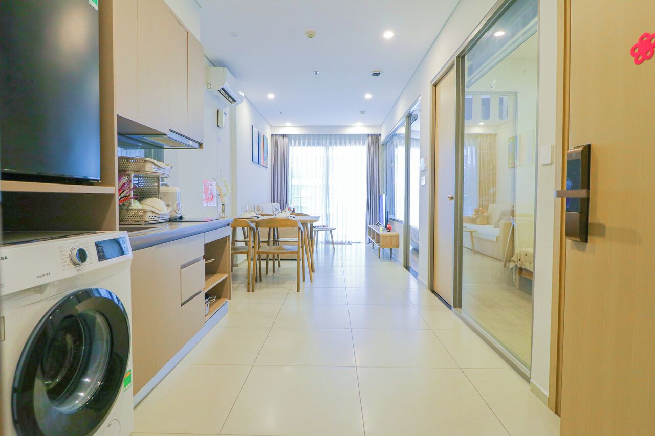 A modern kitchen with a washing machine, a dining area with chairs, and a large window.