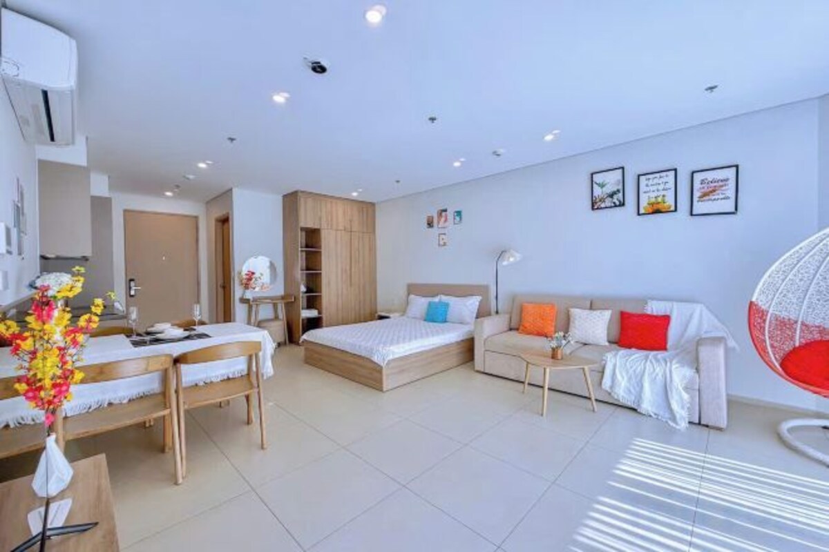 A modern hotel room with a bed, a sofa, a dining area, and a workspace.