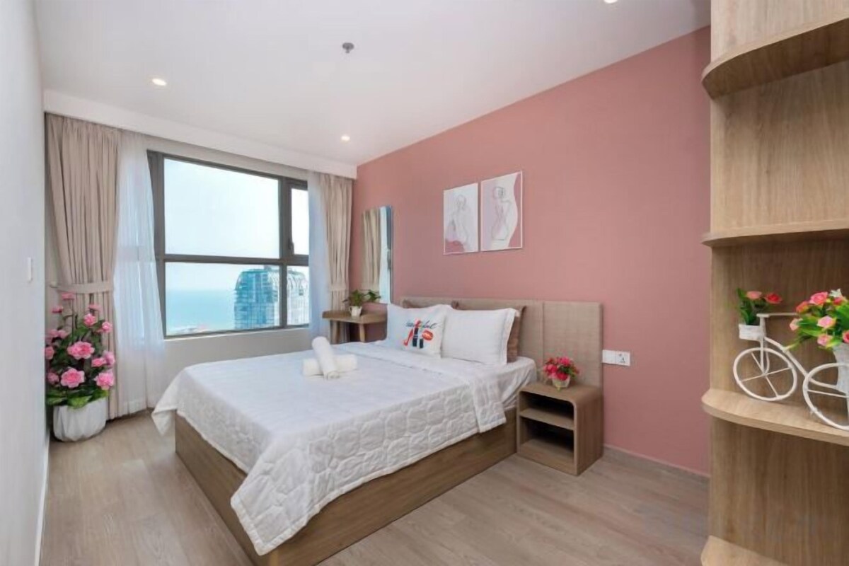 Une chambre d’hôtel avec un grand lit, une table de chevet, une commode, une fenêtre avec des rideaux et une vue sur la ville.