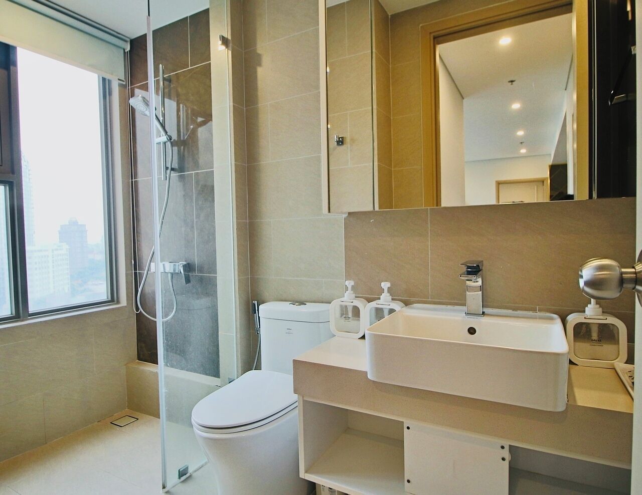 Ein modernes Badezimmer mit Duschkabine aus Glas, Toilette und Waschbecken mit Seifenspendern.