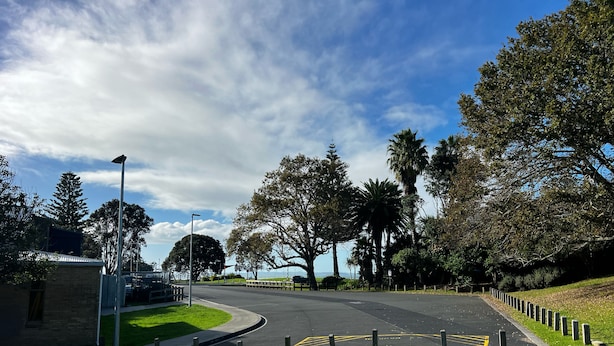 A road with a curved path, surrounded by trees and a grassy area. - Waiake Beach Apartments (Auckland)
