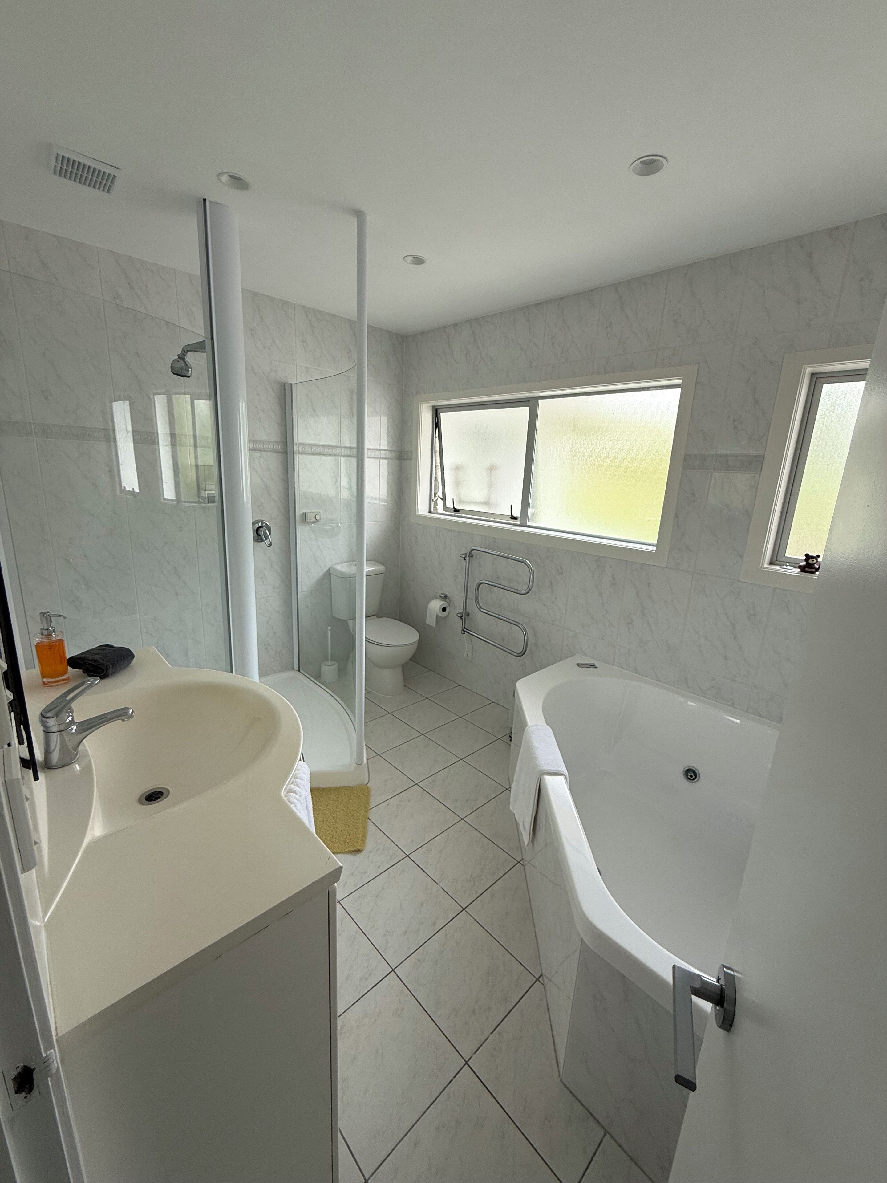 A modern bathroom with a glass-enclosed shower, a toilet, a bathtub, and a sink.