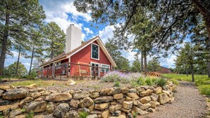 Une cabane à l’extérieur rouge, avec des fondations en pierre et une terrasse en bois.