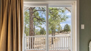 Une vue à travers une porte vitrée à cadre blanc, donnant sur un espace extérieur avec des arbres et un ciel dégagé.