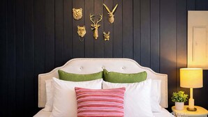 Un lit avec des oreillers blancs et verts, un oreiller à rayures et une tête de lit à motifs capitonnés.