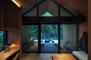 Un interior moderno con un gran ventanal que da a una terraza exterior con una chimenea y asientos.