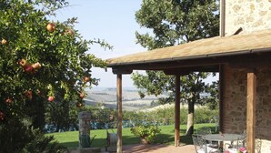 A covered outdoor area with a stone wall, a table with chairs, and a view of a valley. - CASALE TRIESTE - APT - CASALE TRIESTE - NUM. 3 (Laiatico)