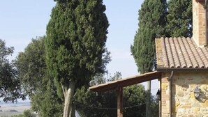 A stone building with a tiled roof, a covered patio with chairs, and a well-maintained lawn. - CASALE TRIESTE - APT - CASALE TRIESTE - NUM. 3 (Laiatico)