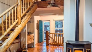 A wooden staircase leading to a room with a fireplace, a door to an outdoor area, and a bear figurine on the floor. - Casa Bella 6 Bedrooms (Ruidoso)