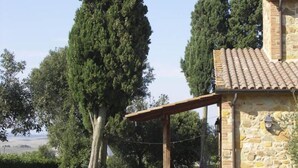 A stone building with a tiled roof, a covered patio with chairs, and a well-maintained lawn. - CASALE TRIESTE - APT - CASALE TRIESTE - NUM. 12 (Laiatico)
