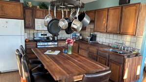 Une cuisine avec des meubles de rangement en bois, une cuisinière, un évier et une table à manger avec des chaises.