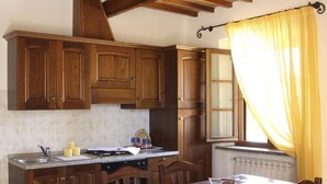 Una cocina con armarios de madera, encimera de granito, estufa y ventana con cortinas amarillas.