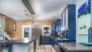 A modern kitchen with a central island, blue cabinets, and a view of the outdoors.
