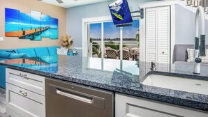 A modern kitchen with granite countertops, a dishwasher, and a view of the outdoors through large windows.