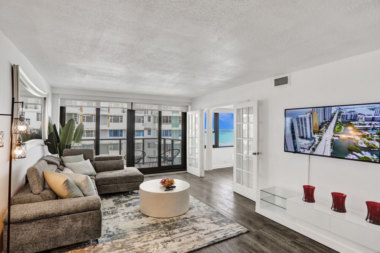 A modern living room with a large window, a flat-screen TV, and a view of a cityscape.