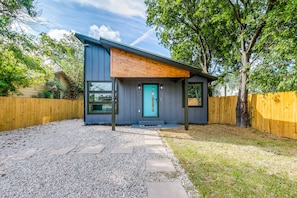 A modern two-story house with a wooden deck, a blue door, and a gravel driveway. - New !!! Modern Home Near The Pearl, Fort Sam & Downtown & Frost Center (San Antonio)