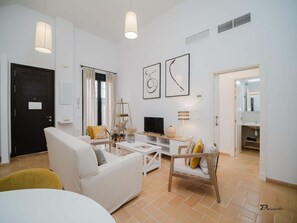 Ein modernes Wohnzimmer mit Sofa, Couchtisch, Fernseher und Kunstwerken an der Wand.