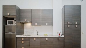 Een moderne keuken met donkerhouten kasten, een roestvrijstalen koelkast, een magnetron en een spoelbak.