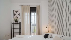 Een slaapkamer met een bed, een ladder, een potplant, een lijst met afbeelding en een kamer met een patroon.