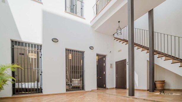Een ruim interieur met een hoge plafond, een trap en een balkon.