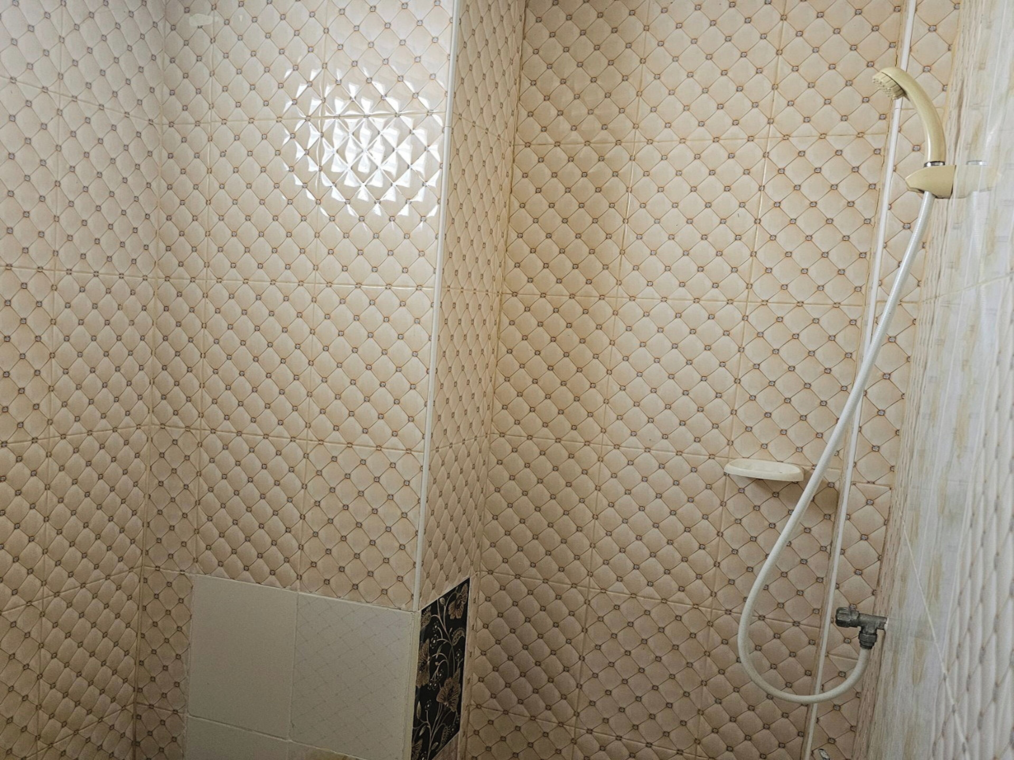 A bathroom with patterned tiles and a shower area.
