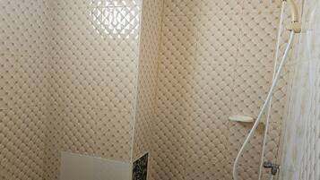A bathroom with patterned tiles and a shower area.