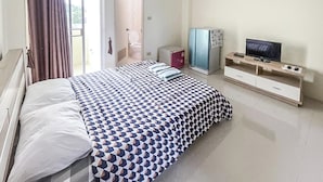 A bedroom with a bed, a television, a wardrobe, and a bathroom visible through an open door. - Orchid Residence At Amata (Phan Thong)