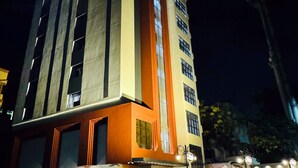 Un hôtel à plusieurs étages, doté d’une façade imposante aux couleurs orange et beige, de grandes fenêtres et d’une entrée bien visible avec des marches.