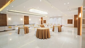Un hall d’hôtel spacieux et moderne, avec des tables et des chaises rondes, un grand lustre et un sol ciré.