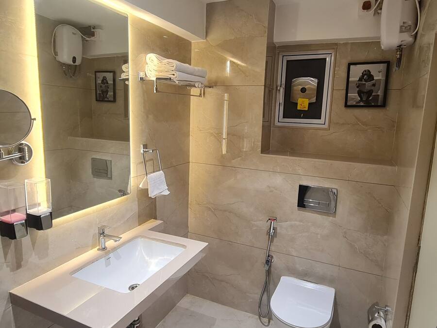 Un baño moderno con un espejo grande, un lavabo, un inodoro y una ducha.