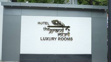 Schild für "Hotel The Grand Luxury Rooms" mit einem Logo aus Feder und Blatt.
