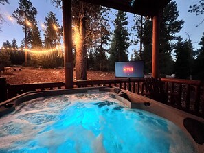 Puinen kuisti, poreallas ja ympärillä puita sekä televisio, jonka näytöllä näkyy Netflixin logo.
