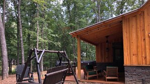Eine Holzhütte mit Veranda, Schaukel und Sitzgelegenheit im Freien.