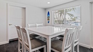 A dining area with a white table and chairs, a door, and a window with blinds. - Waterfront with Pool, Ping Pong table, 3 Kayaks, Fishing Pier, Private Access to the Gulf (Port Richey)