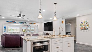 A modern kitchen with white cabinetry, stainless steel appliances, and a marble countertop. - Waterfront with Pool, Ping Pong table, 3 Kayaks, Fishing Pier, Private Access to the Gulf (Port Richey)