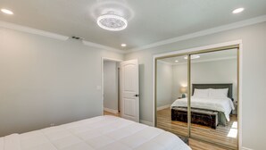 Une chambre à coucher avec un grand lit, un miroir et une porte donnant sur une autre pièce.