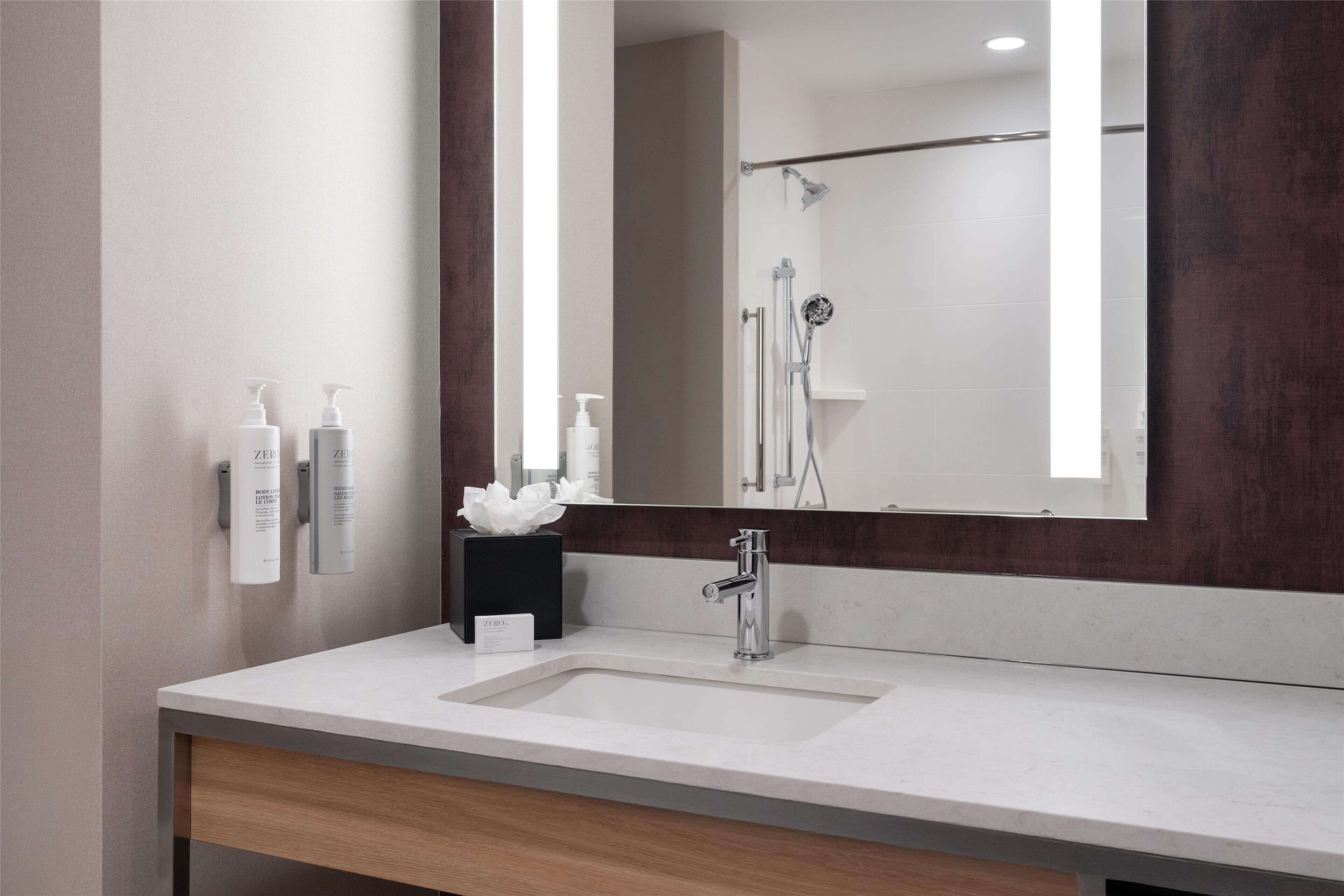Un baño moderno con un espejo grande, un lavabo y una zona de ducha.
