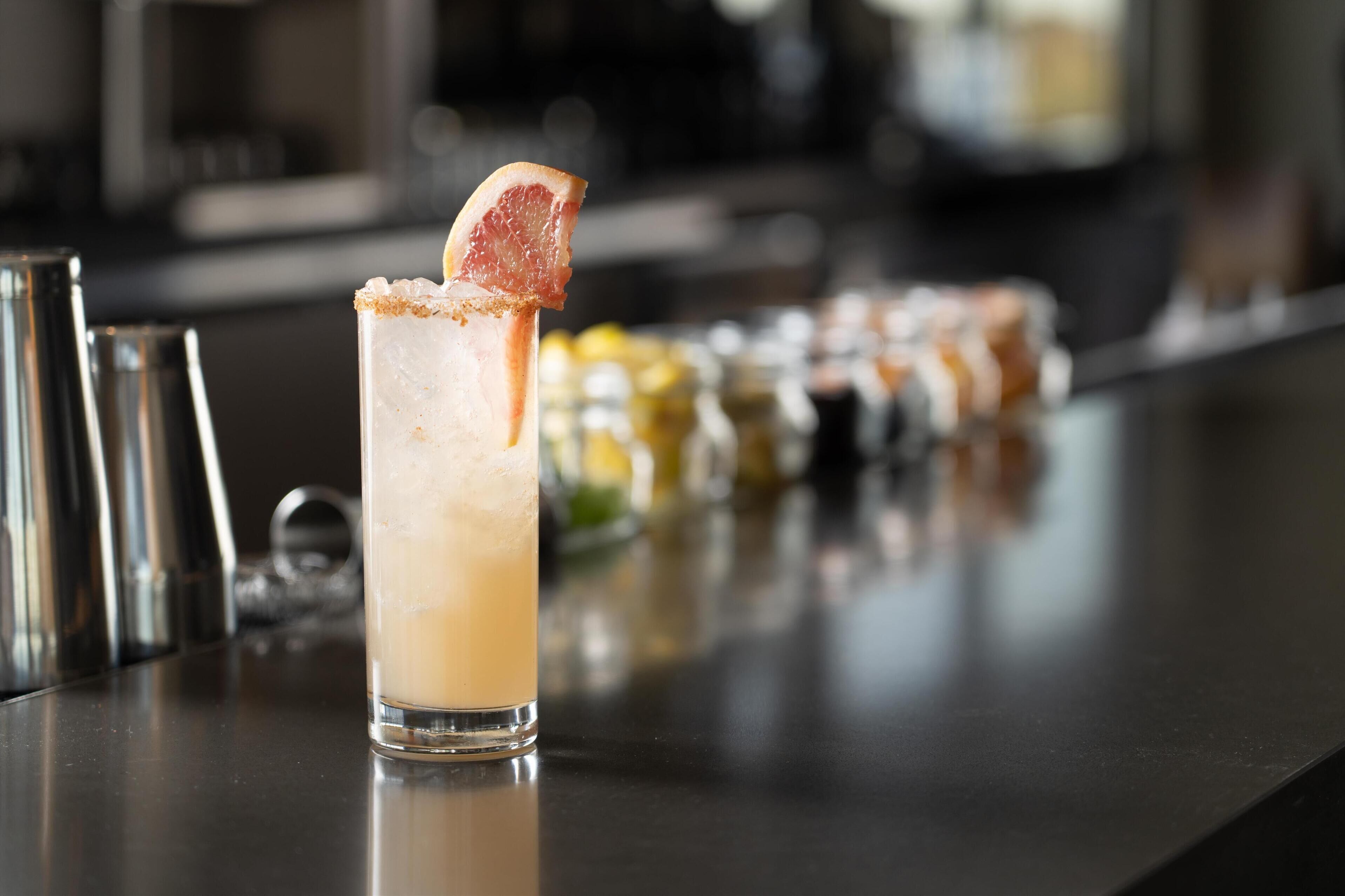 A cocktail glass with a citrus garnish on a bar counter.